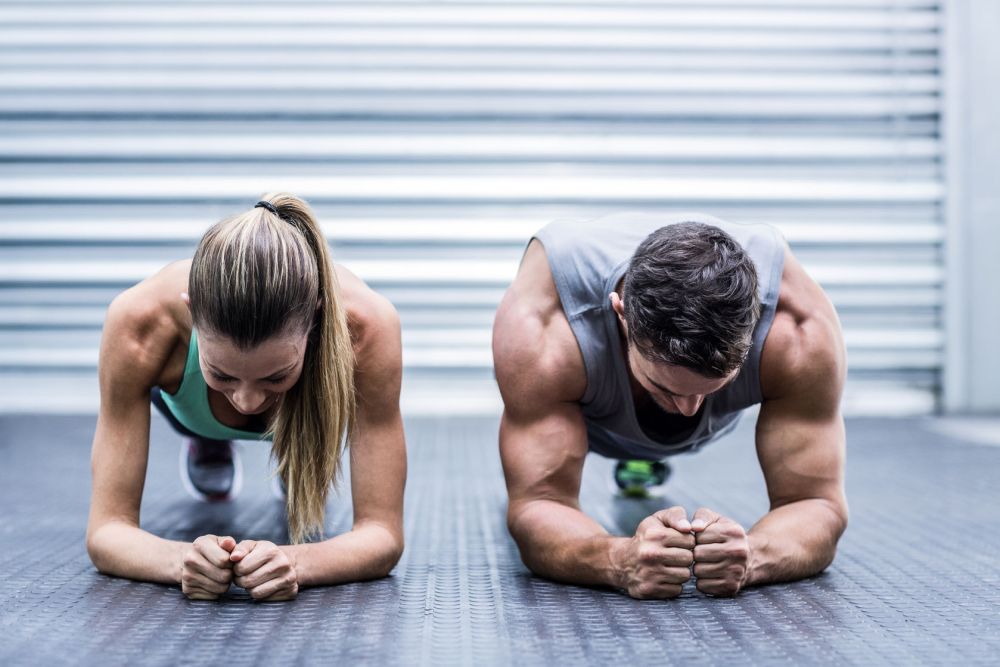42329549 - front view of a muscular couple doing planking exercises